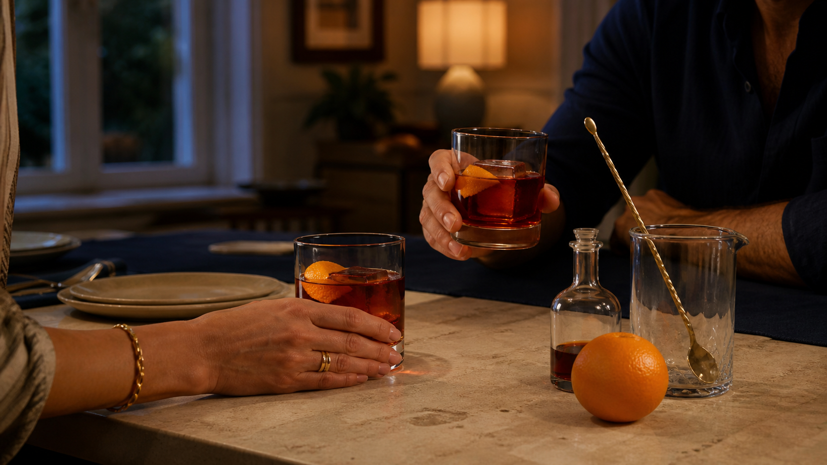 Two adults sharing ruby-orange reposado Rosita cocktails at a warm dinner table